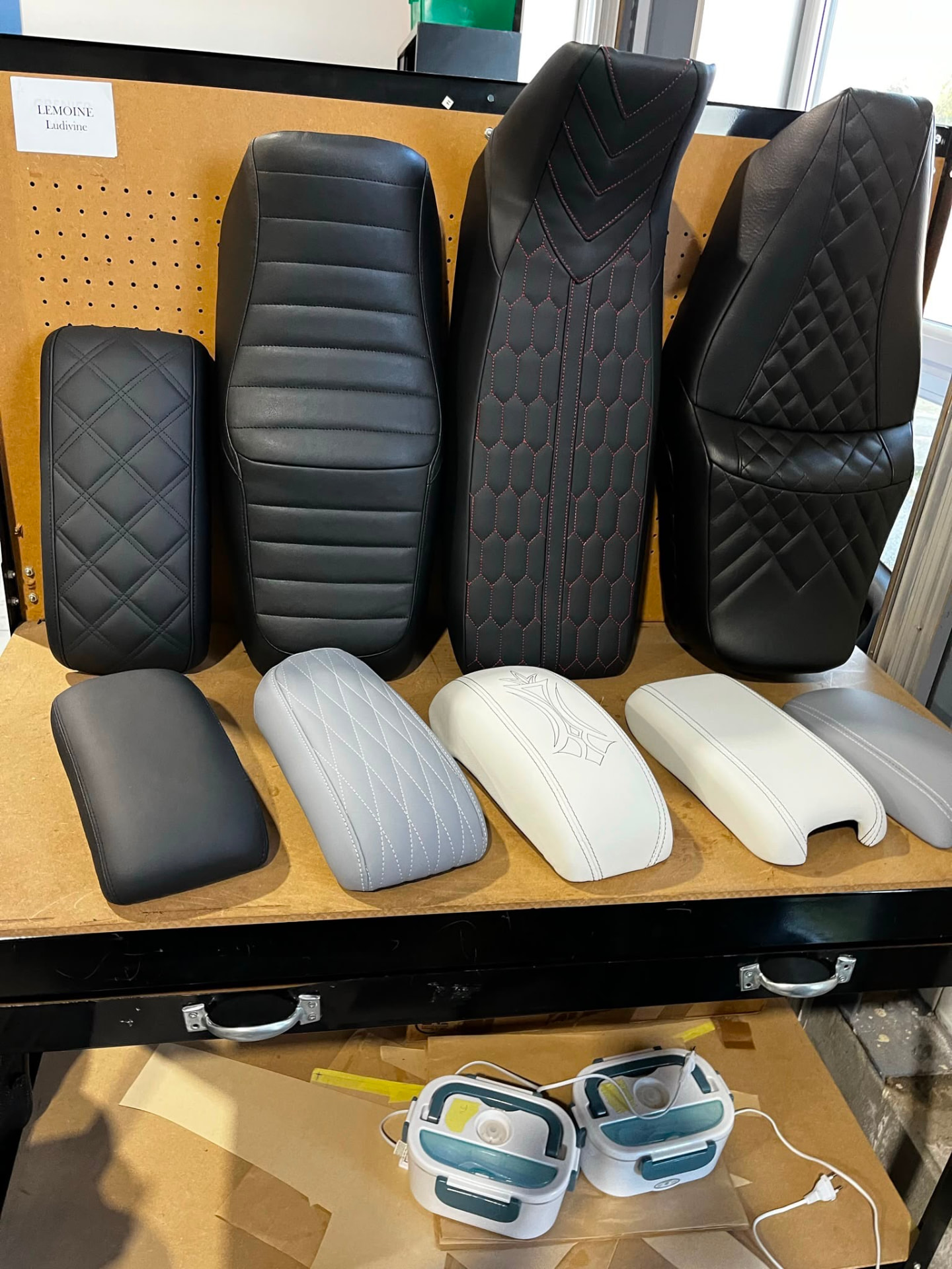 Série de selles de moto recouvertes de cuir noir, gris et blanc à l'atelier